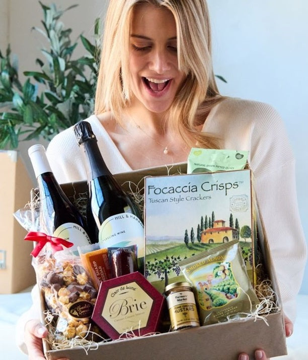 Picture of a women holding the two California red and white bottle Charcuterie gift basket for delivery 